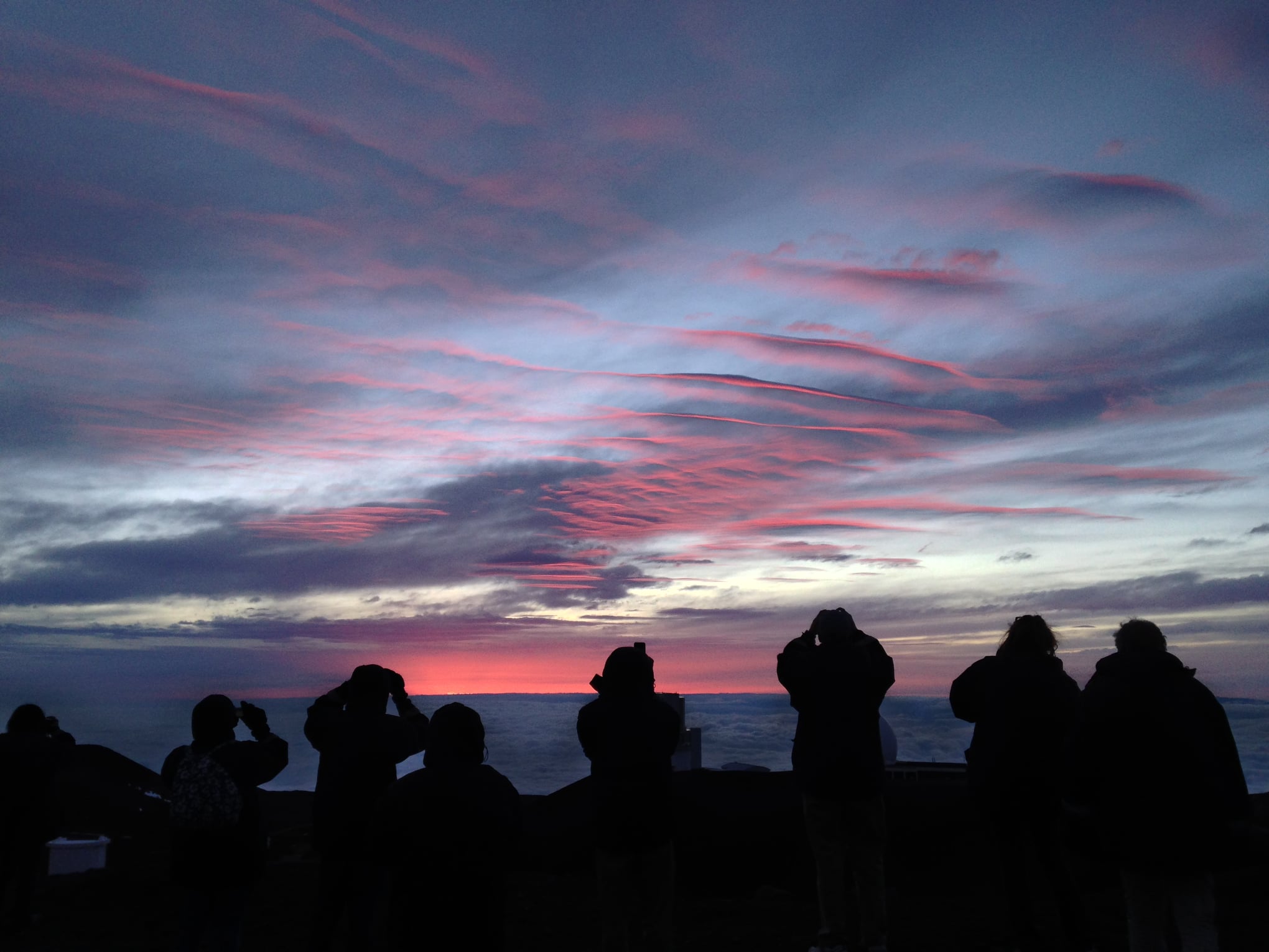 a group of people standing in front of a sunset
