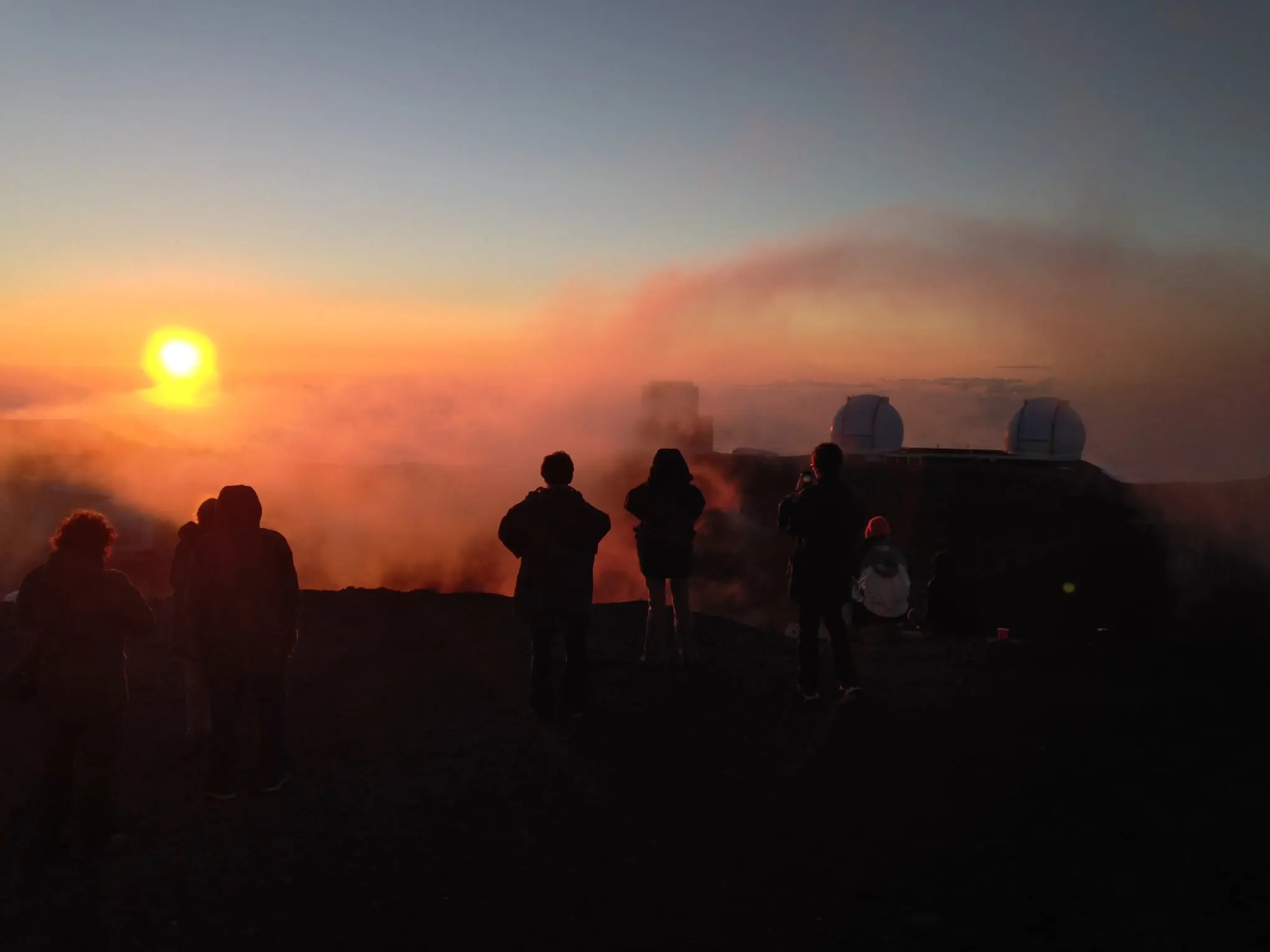 a group of people standing in front of a sunset