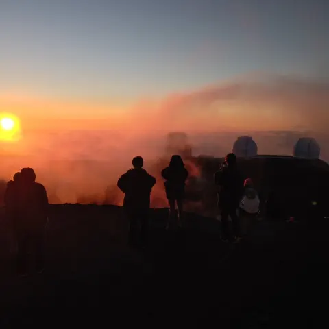 a group of people standing in front of a sunset
