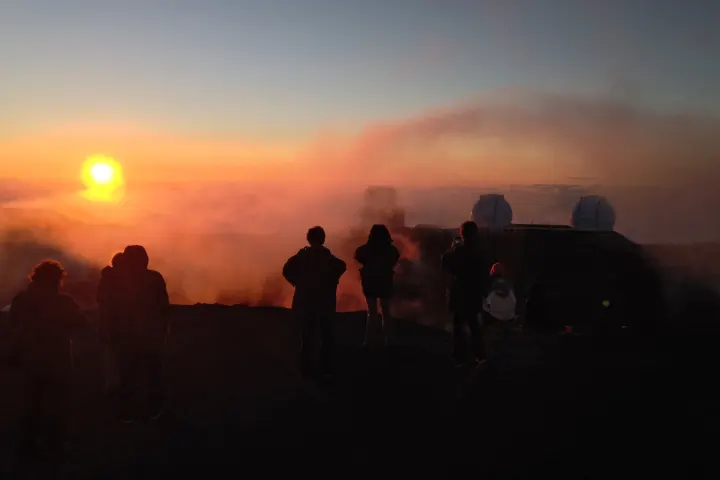 a group of people standing in front of a sunset