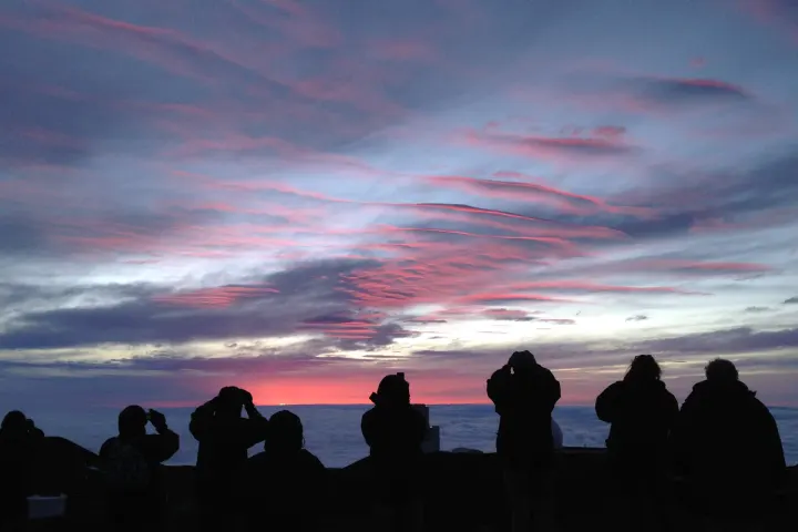a group of people standing in front of a sunset