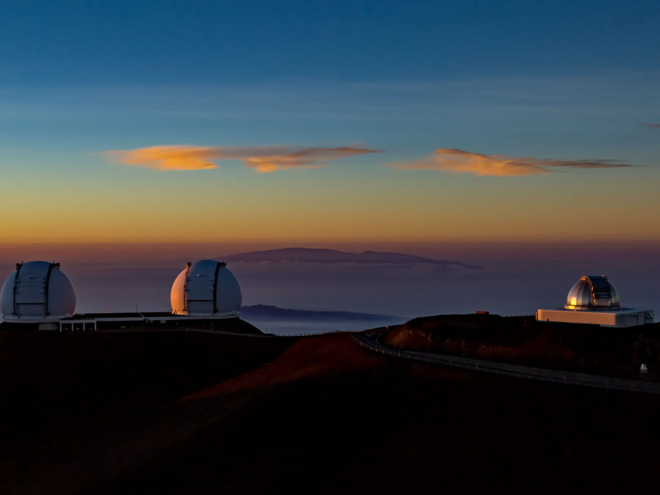 a sunset over a body of water with Mauna Kea in the background